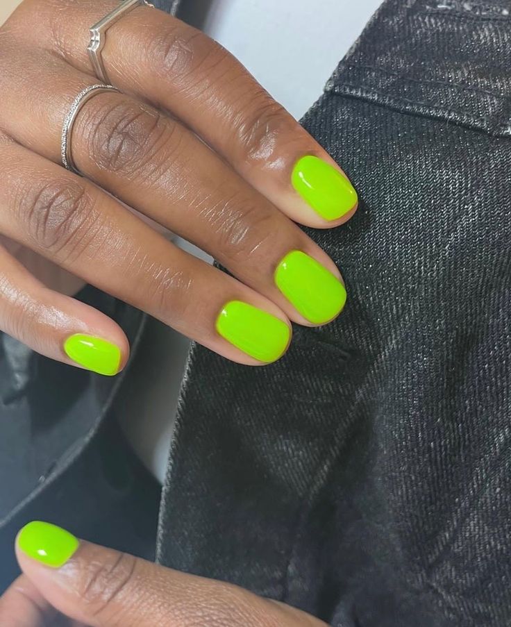 Mãos de pele preta, com anéis em prata e unha curta e arredondada amarelo-neon 