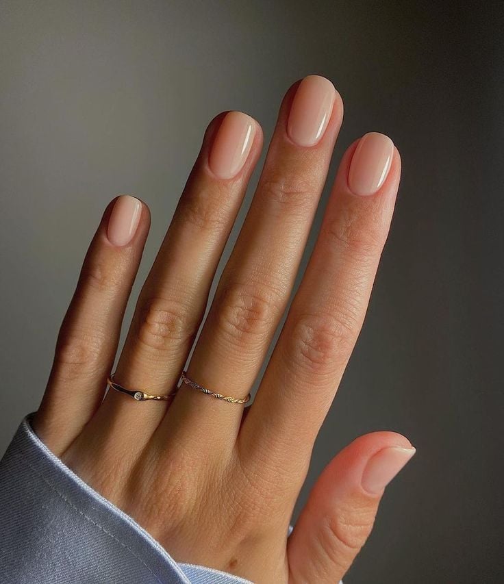Mão de pele clara, com anéis em dourado e unha curta e squoval natural