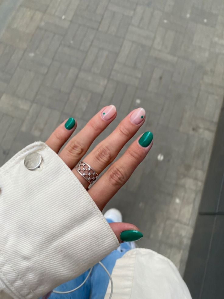 Mão de pele clara, com anel em prata, unha curta amendoada verde com decoração minimalista