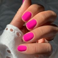 Mão de pele clara, com unha curtinha rosa neon