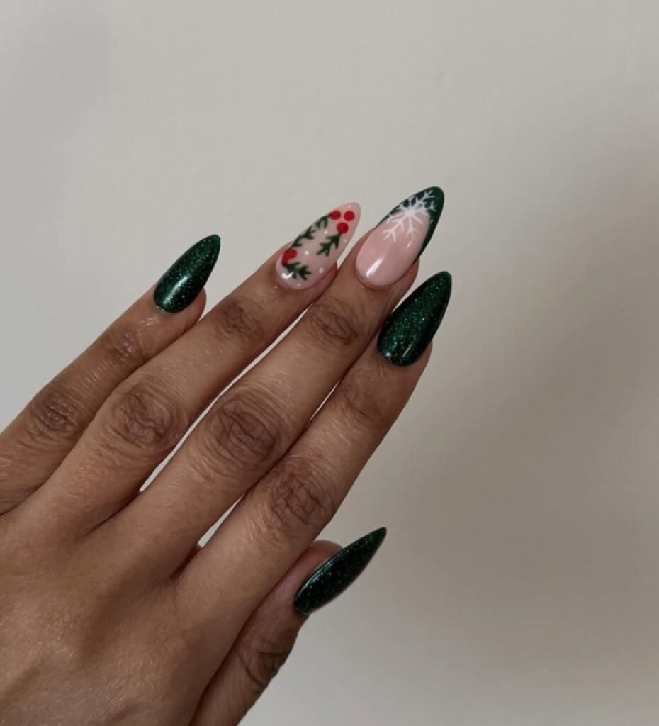 Mão de pele preta, com unha amendoada verde decorada com itens de Natal 