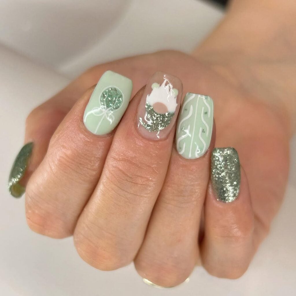 Mão de pele branca, com unha quadrada verde-pastel com decorações de Natal 