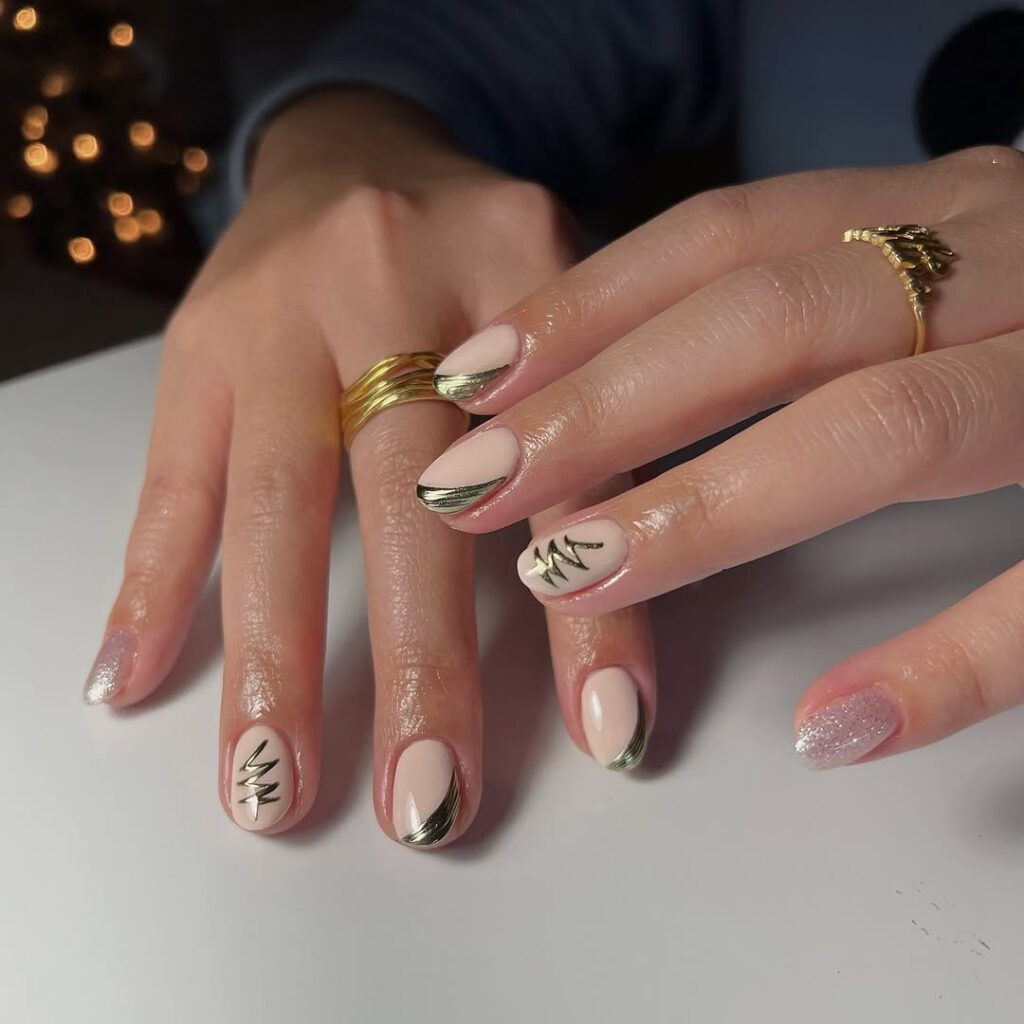 Mãos de pele clara, com acessórios em dourado e unha amendoada curta nude com decorações em dourado 