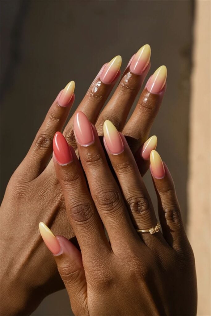 Mãos de pele preta, com acessórios em dourado e unha amendoada ombré colorida