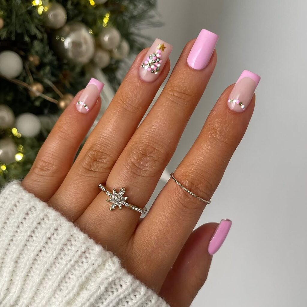 Mão de pele clara, com acessórios em prata e unha quadrada rosa com decoração de Natal