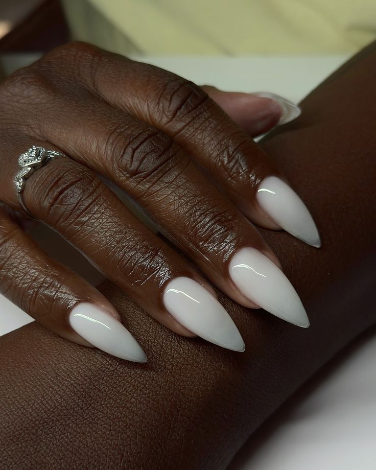 Mão de pele preta, com acessório em prata e unha stiletto branca