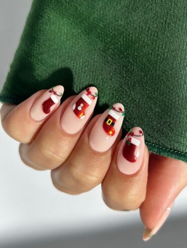 Mão de pele clara, com unha amendoada nude decorada com bota de Natal