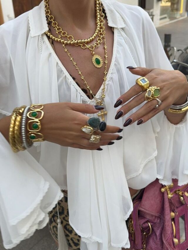 Mulher de pele clara, com bata branca e acessórios em dourado