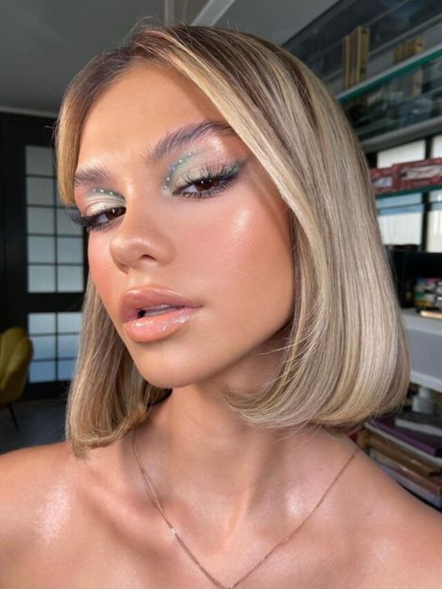 Mulher de pele clara, com cabelo loiro corte bob e maquiagem com delineado gráfico com pedras