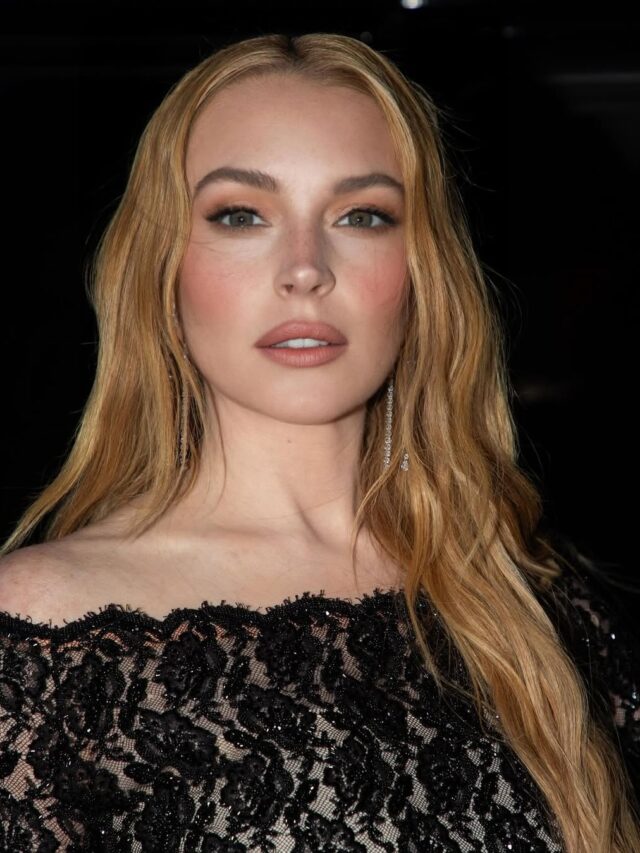 Lindsay Lohan, com vestido de tule preto, cabelo liso loiro e maquiagem clean