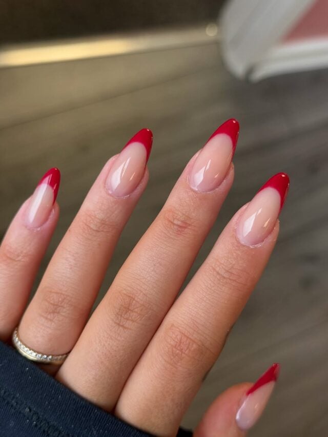 Mão de pele branca, com unha em formato amendoado com nail art de francesinha vermelha