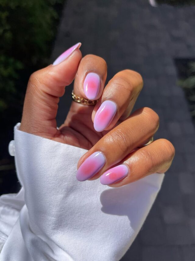 Mão de pele negra, com nail art aura nails, nas cores lilás e rosa