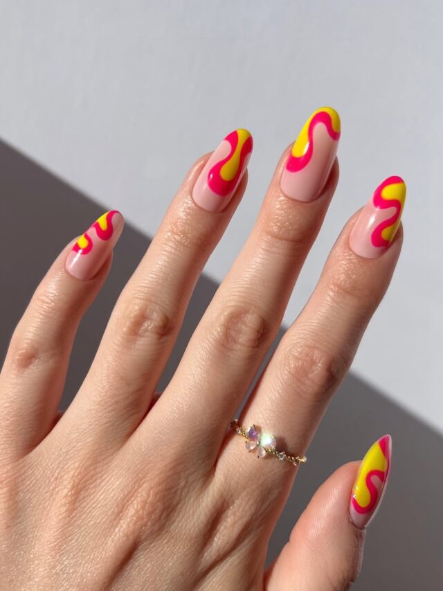 Mão de pele clara, com anel em dourado e unha amendoada nude com decorações em neon