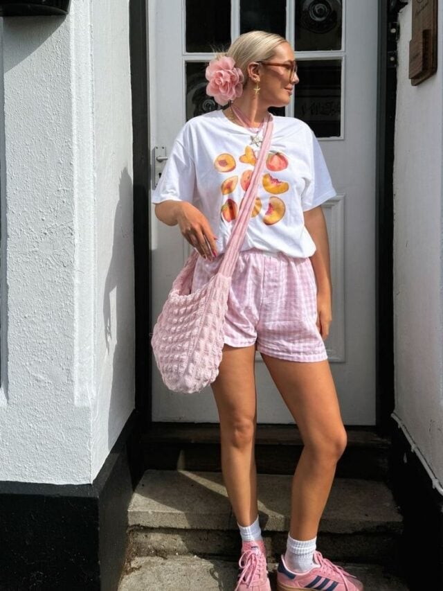 Mulher jovem e magra com pele clara. Ela usa camiseta branca estampada e bermuda.