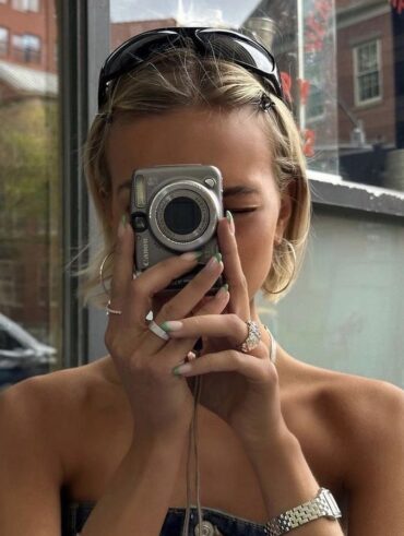 Mulher jovem de pele clara e cabelois loiros tirando foto com câmera cybershot