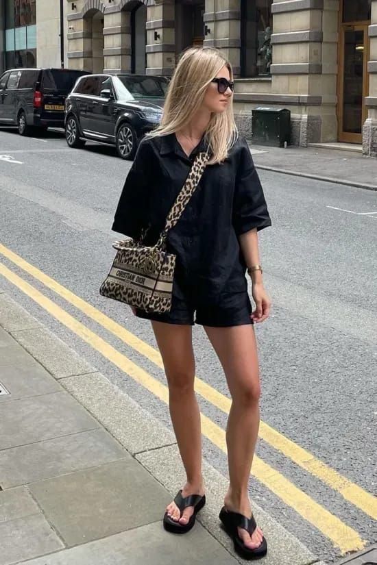 Mulher jovem e magra com look preto com chinelo plataforma