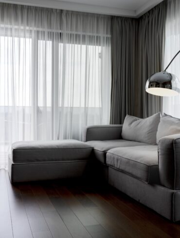 Sala de estar com cortina e sofá cinza