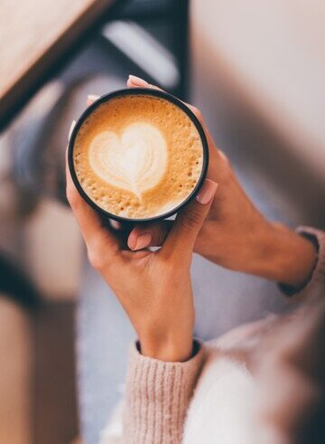 Mão branca segurando xícara de café