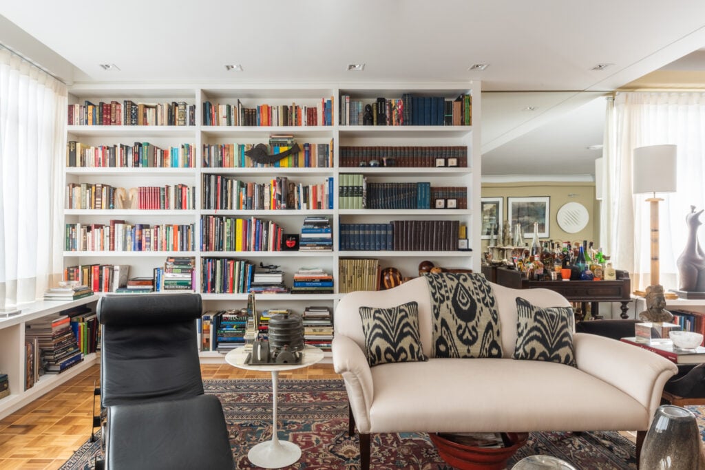 Sala de estar com sofá branco e estante grande de livros
