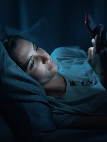 Mulher deitada no escuro mexendo no celular