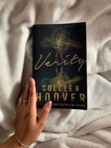 Ao fundo uma coberta branca, com o livro Verity em cima