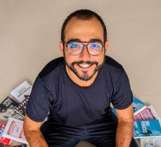 Raphael Montes sentado com livros ao redor