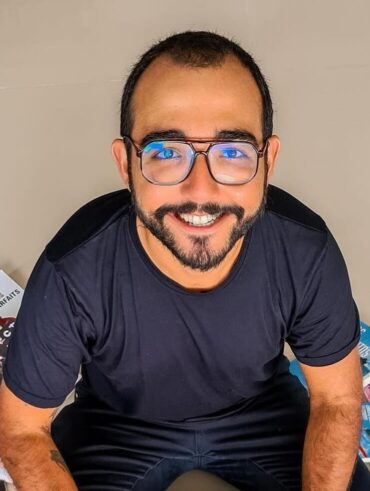 Raphael Montes sentado com livros ao redor