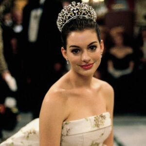 Anne Hathaway com vestido tomara que caia, cabelo preso com coroa e rom-com lips
