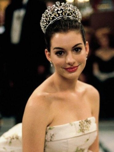 Anne Hathaway com vestido tomara que caia, cabelo preso com coroa e rom-com lips