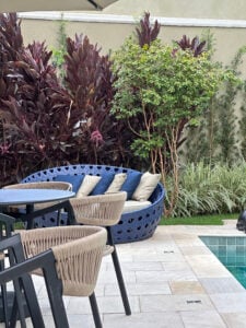 Área externa junto à piscina, com plantas, cadeiras e sofá