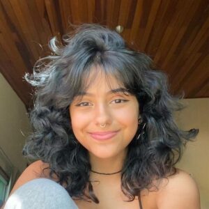 Mulher branca com cabelo preto, curto e em camadas com franja