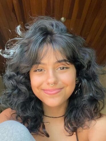 Mulher branca com cabelo preto, curto e em camadas com franja