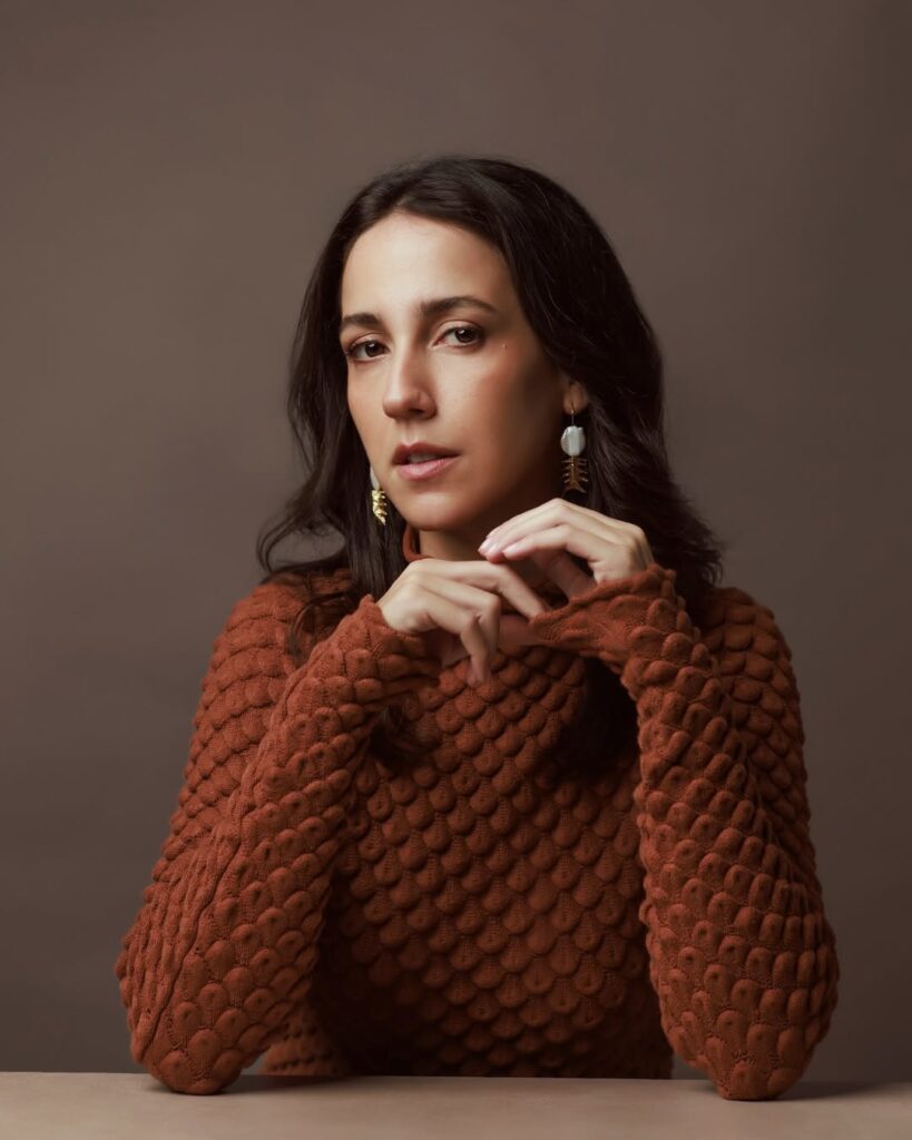 Camila Márdila, com cabelo preto e blusa texturizada terracota