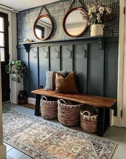 Hall de entrada com parede escura, ganchos, espelhos redondos e cestos organizadores