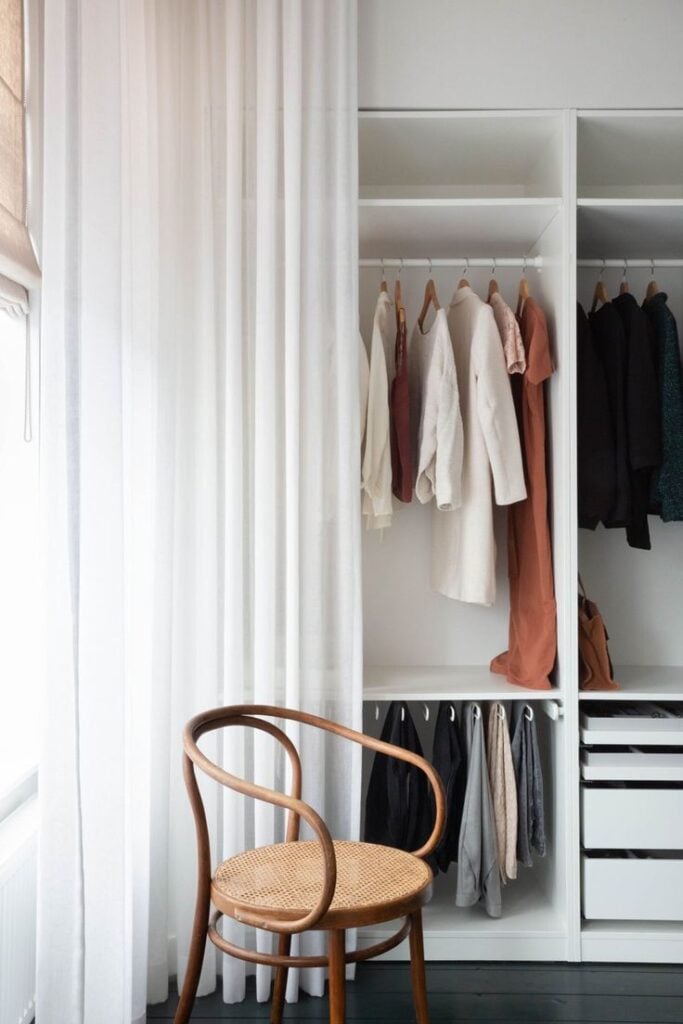 Closet branco com cortina branca e cadeira de madeira