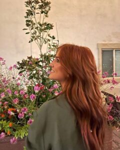 Mulher de pele clara, com camisa verde e cabelo ruivo saudável