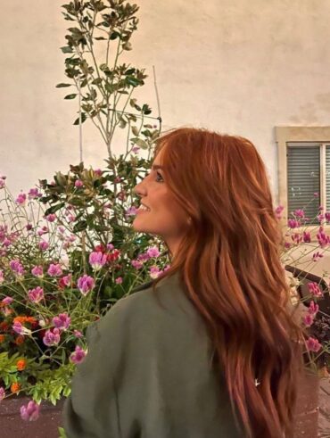 Mulher de pele clara, com camisa verde e cabelo ruivo saudável