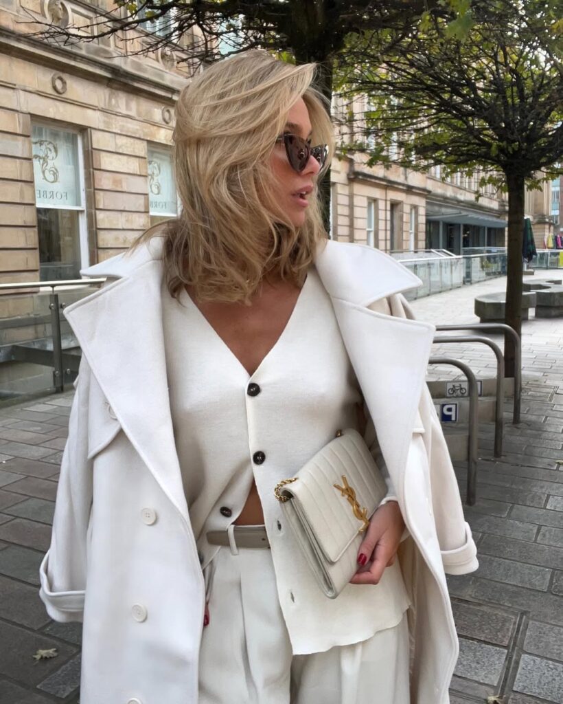 Mulher de pele clara, com look all-white e cabelo loiro com corte gatinho