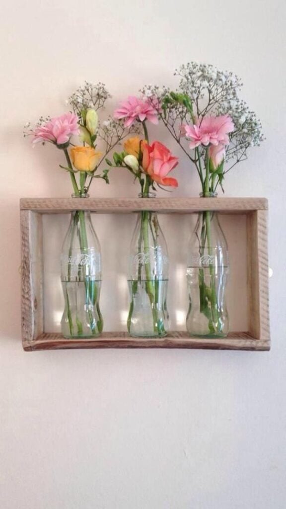 Quadro de madeira com garrafas de vidro e flores