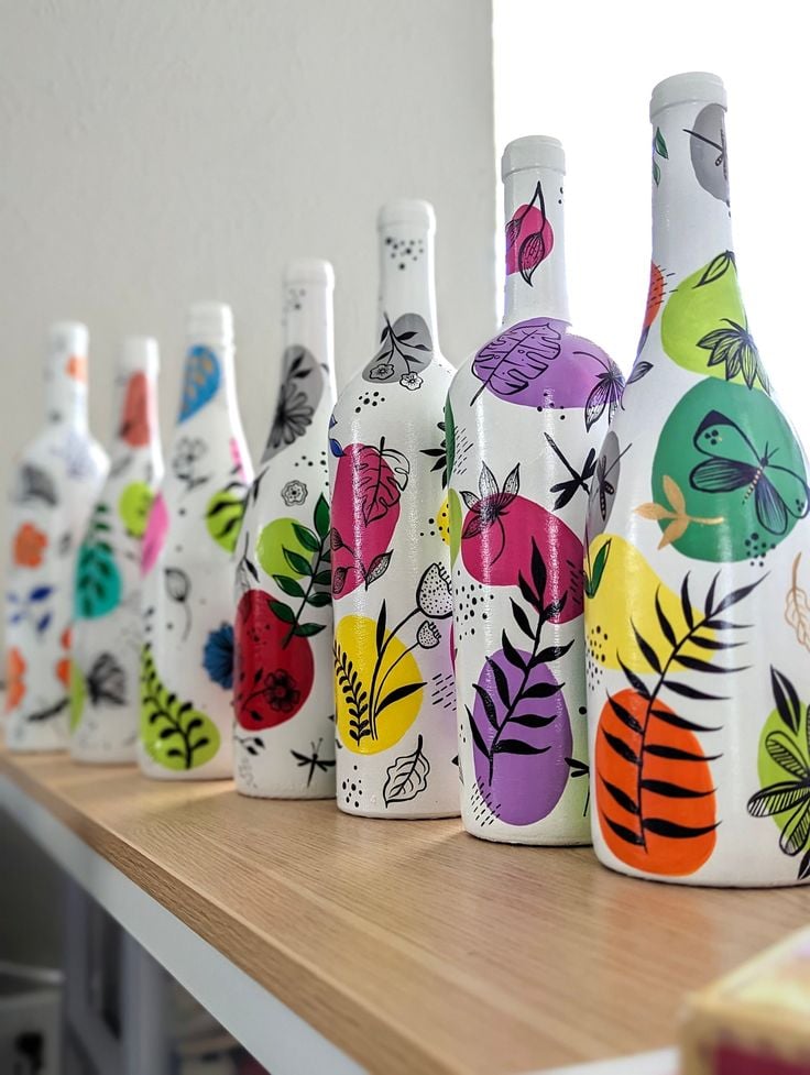 Garrafas pintadas de branco e decoradas com desenhos e cores variadas
