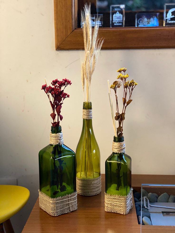 Garrafas de vidro pintadas de verde com flores secas