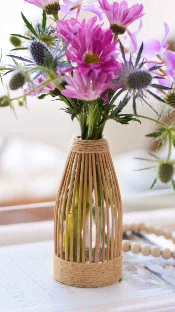 Garrafa revestida com palitinhos e cisal, com flores