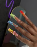 Mão de pele preta, com duck nails e francesinhas coloridas e com texturas diferentes