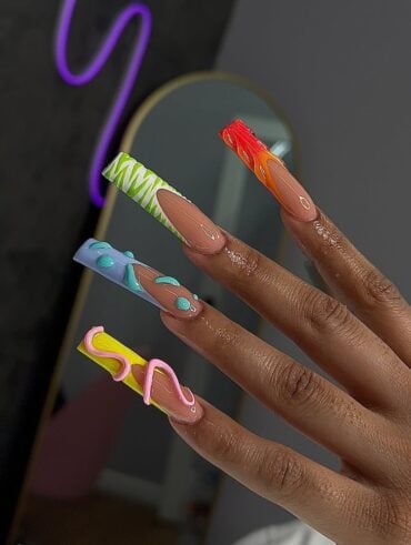 Mão de pele preta, com duck nails e francesinhas coloridas e com texturas diferentes