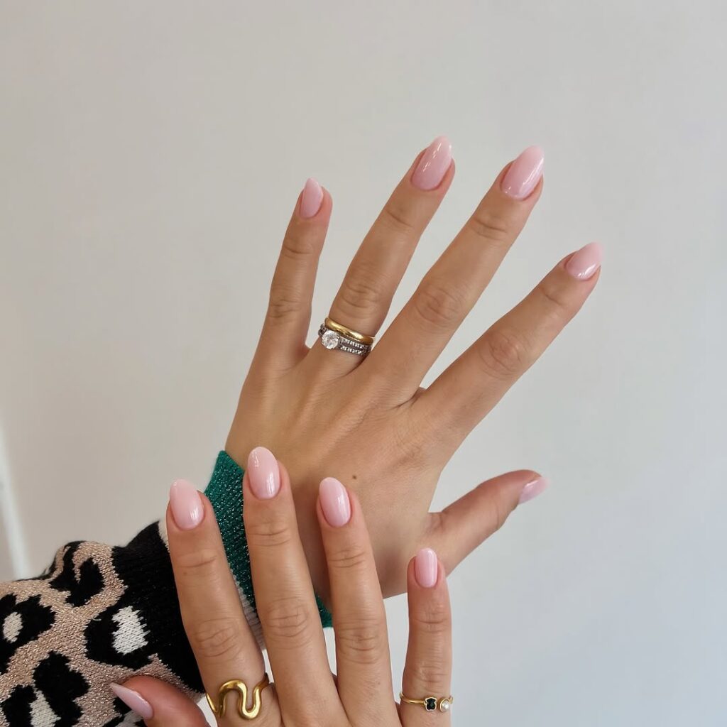 Mãos de pele clara, com acessórios em prata e dourado e unha amendoada estilo soap nails 