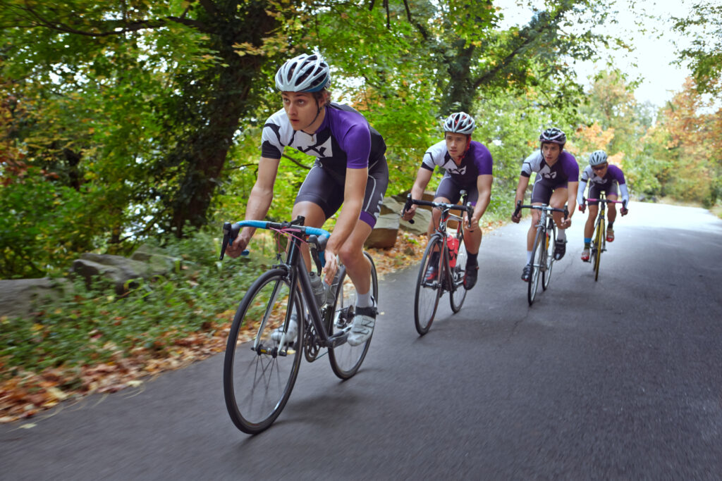 Grupo de quatro ciclistas em uma estrada arborizada