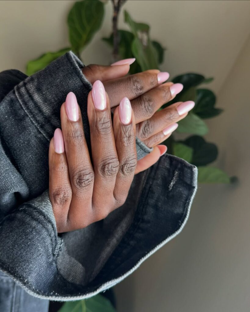 Mãos de pele negra, com unha longa e amendoada e esmalte rosa com nail art glazed donut nails