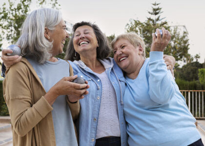 Três mulheres idosas abraçadas rindo