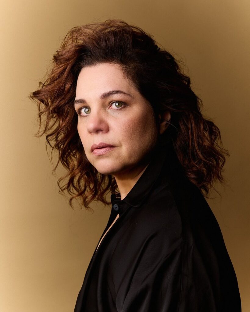 Isabel Teixeira, com look preto e cabelo ondulado solto