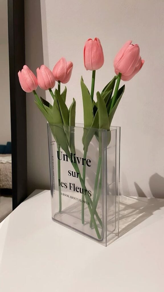 Vaso transparente em formato de livro com tulipas rosas